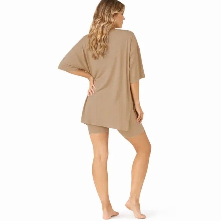 A woman modeling a loose-fitting beige short-sleeve tunic top and matching fitted shorts against a plain white studio background.